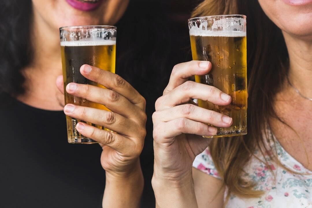 women holding two glasses of beer